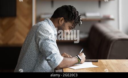 Il ragazzo africano siede al tavolo compila il questionario di indagine sulle informazioni Foto Stock