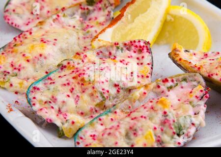 Le cozze kiwi, note anche come verdi, verdi-lipped, giganti e Nuova Zelanda, cotte al forno con salsa al formaggio, peperone, parmigiano, roe di pesce volante tobiko. Foto Stock