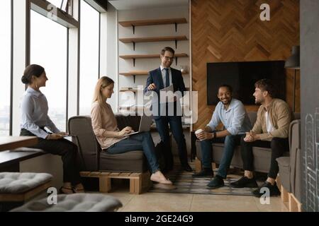 Cinque diversi membri dello staff riuniti in ufficio risolvono l'attività corrente Foto Stock