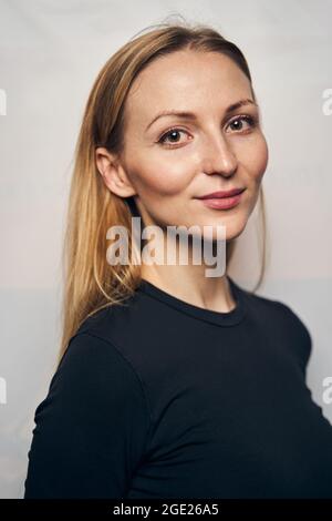 Tranquilla splendida signora che posa per la macchina fotografica contro il muro Foto Stock