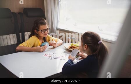 Bambine che giocano le carte all'interno in caravan, viaggio di vacanza in famiglia. Foto Stock