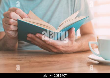 Uomo che legge libro a casa, godendo di una buona lettura da solo, fuoco selettivo Foto Stock