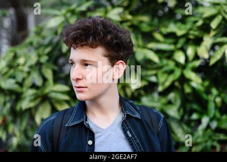 Primo piano ritratto del giovane uomo su sfondo verde all'aperto. Foto Stock