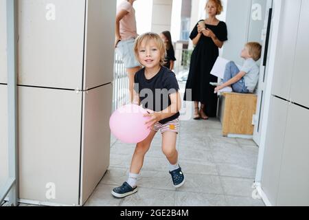 Il ragazzino corre con un palloncino rosa verso la fotocamera. Foto Stock