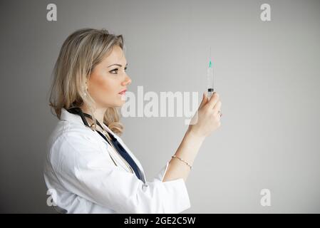 Medico donna con siringa si sta preparando per l'iniezione isolato su sfondo grigio Foto Stock