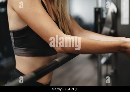 Primo piano di una donna che si appoggia sul barbell in palestra mentre si esercita Foto Stock