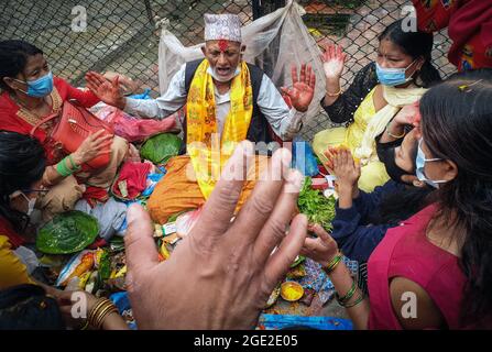 Kathmandu, Bagmati, Nepal. 16 agosto 2021. Le donne nepalesi partecipano ai rituali religiosi con un sacerdote mentre offrono preghiere su Shrawan Somvar ad un tempiale di Shiva in mezzo all'epidemia di COVID-19 a Kathmandu, capitale del Nepal il 16 agosto 2021. Lunedì o Somvars del mese santo Shrawan sono considerati favorevoli come la gente veloce ed offrire le preghiere al Signore Shiva, specialmente le donne digiunano & pregano per una vita prospera e lunga dei loro mariti o desiderano trovarne una buona. (Credit Image: © Sunil Sharma/ZUMA Press Wire) Credit: ZUMA Press, Inc./Alamy Live News Foto Stock