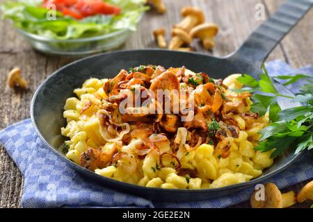 Spaetzle vegetariano tedesco con chanterelle fritte e cipolle servite in una padella Foto Stock