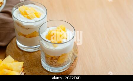 Gustosi dessert di ananas con sminuzzati di ananas fresco e succoso. Dessert per la colazione con granola di avena, yogurt greco e ananas a strati in vetro Foto Stock