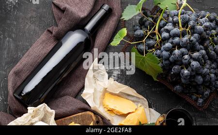 Bottiglia di vino rosso, diversi formaggi, uve. Composizione del vino d'annata ancora da vita con formaggio Camembert affinato, uva. Cena al ristorante, degustazione di vini Foto Stock