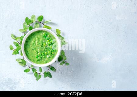 Zuppa vegana con piselli verdi e menta, top shot con spazio copia. Pranzo sano detox. Cibo biologico Foto Stock
