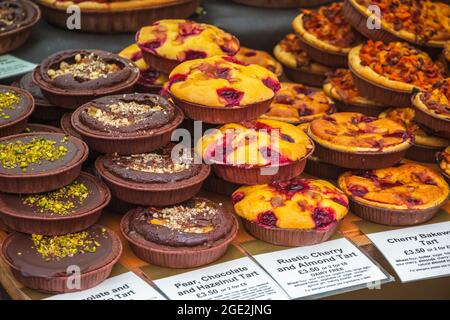 Assortimento di torte dolci in mostra al Broadway Market, un mercato di strada a Hackney, Londra Est Foto Stock