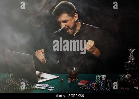 Uomo bearded del giocatore in linea del casino che celebra la vittoria Foto Stock
