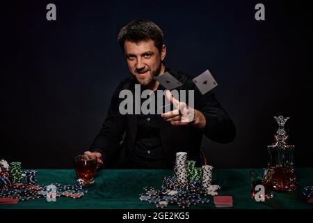 Uomo giocatore di casinò bearded che gioca a poker su tavolo verde Foto Stock