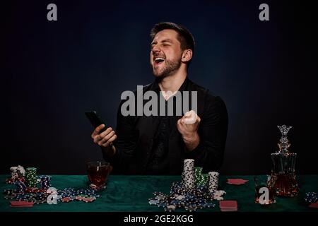 Uomo giocatore di casinò bearded che gioca a poker su tavolo verde Foto Stock