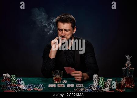 Uomo giocatore di casinò bearded che gioca a poker su tavolo verde Foto Stock