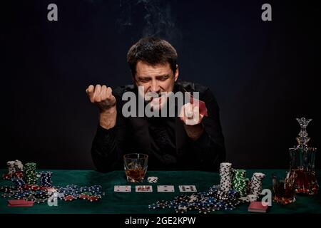 Uomo giocatore di casinò bearded che gioca a poker su tavolo verde Foto Stock