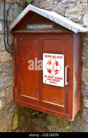 Herm, Isole della Manica, Regno Unito - 2 luglio 2016: Telefono pubblico in wodden muro armadio e le istruzioni di sicurezza a Rosaire o Rosiere gradini. Foto Stock