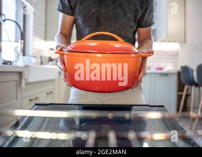 Un uomo tiene un piatto in mano prima di metterlo in forno. Foto Stock