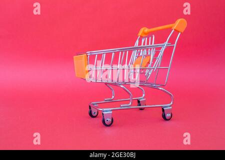 Mini carrello isolato su sfondo rosa con spazio per la copia. Concetto di shopping. Foto Stock