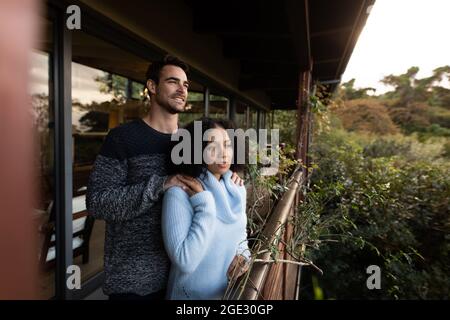 Felice coppia diverse sul balcone insieme abbracciando parlare e sorridendo Foto Stock