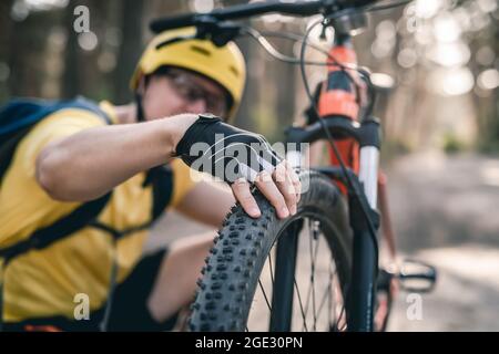 Ciclista uomo che controlla la pressione degli pneumatici Foto Stock