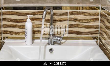 L'acqua scorre da un rubinetto d'acqua in metallo. Primo piano. Foto Stock