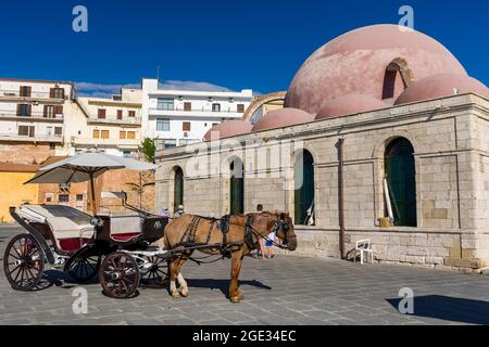 Cavalli e carrozze sul lungomare vicino all'antica moschea di Chania, Creta, Grecia Foto Stock