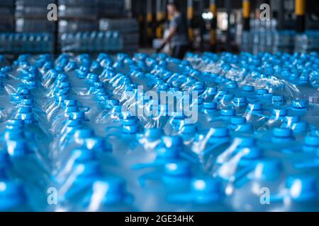 Le caraffe d'acqua in plastica blu confezionate si trovano nel magazzino dei prodotti finiti. Immagine di sfondo. Produzione alimentare Foto Stock