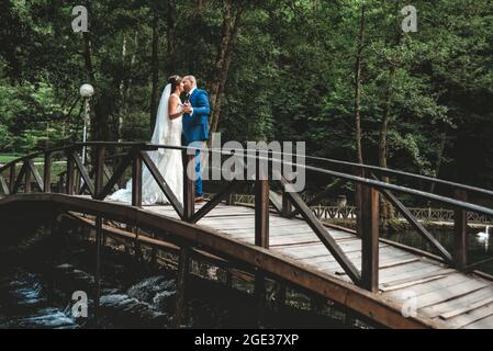 Bella sposa in elegante abito da sposa bianco con velo lungo e sposo in abito blu Foto Stock