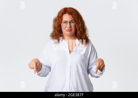 Deluso e frustrata donna rossa di mezza età in occhiali lamentando cattivo servizio, aspetto scettico e non divertito, grimacing e accigliare Foto Stock