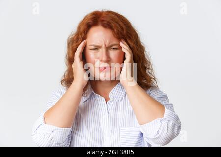 Concetto di persone, emozioni e stile di vita. Primo piano di una donna che avverte capogiri o malessere, grimacing da mal di testa, templi a contatto, emicrania, bisogno Foto Stock
