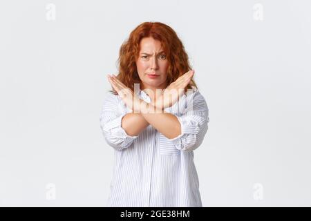 Donna di mezza età gravemente delusa e irritata, donna rossa che mostra stop, gesto trasversale, che guarda infastidito o alimentato, proibiscono l'azione Foto Stock