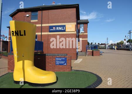 Scarponi gialli RNLI sulla passeggiata fuori dall'edificio del battello di salvataggio Barry Island, Galles del Sud, Regno Unito, agosto 2021 Foto Stock