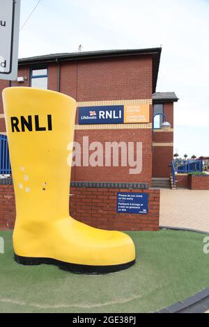 Scarponi gialli RNLI sulla passeggiata fuori dall'edificio del battello di salvataggio Barry Island, Galles del Sud, Regno Unito, agosto 2021 Foto Stock