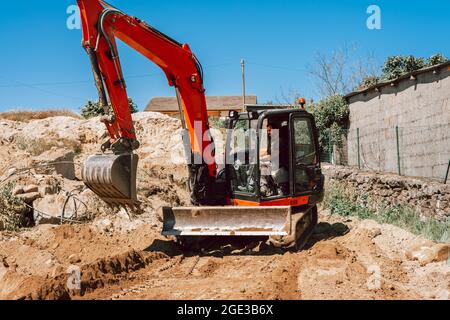 Lavoratore che guida un escavatore in un cantiere. Foto Stock