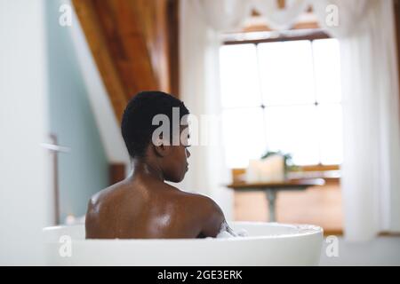 Donna afroamericana sorridente in bagno, rilassante in bagno Foto Stock