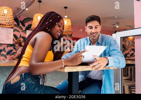 Amici multiculturali seduti in un ristorante e leggendo il menu insieme. Foto Stock