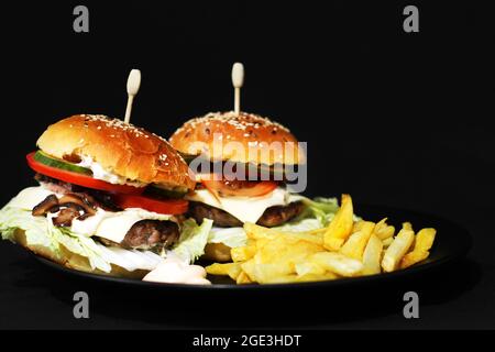 Hamburger e patatine fritte fatti in casa. Fast food fatto in casa. Cuoci con semi di sesamo e ripieno. Sandwich grande Foto Stock