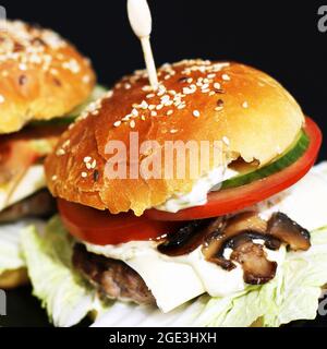 Hamburger succulento fatto in casa. Fast food fatto in casa. Cuoci con semi di sesamo e ripieno. Sandwich grande Foto Stock