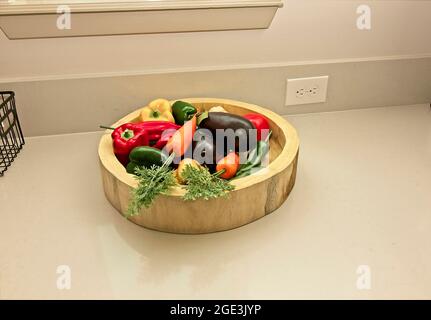Ciotola di legno di ortaggi artificiali su bancone da cucina Foto Stock