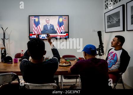 La gente guarda il discorso del primo ministro Muhyiddin Yassin su uno schermo televisivo a Kuala Lumpur.il primo ministro malese Muhyiddin Yassin ha annunciato le sue dimissioni durante una conferenza stampa ufficiale presso l'ufficio del primo ministro (PMO) a Putrajaya. Foto Stock