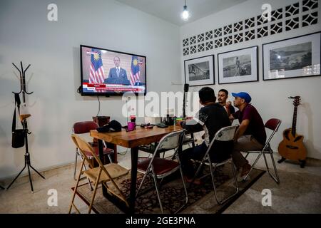 La gente guarda il discorso del primo ministro Muhyiddin Yassin su uno schermo televisivo a Kuala Lumpur.il primo ministro malese Muhyiddin Yassin ha annunciato le sue dimissioni durante una conferenza stampa ufficiale presso l'ufficio del primo ministro (PMO) a Putrajaya. Foto Stock