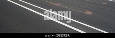 Strada pulita con linee di marcatura parallele bianche e vecchio segnale giallo di svolta a U. Foto Stock