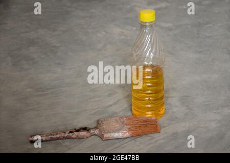 Closeup il colore giallo tar peen bottiglia di plastica vecchia vernice pennello su sfondo grigio fuori fuoco Foto Stock