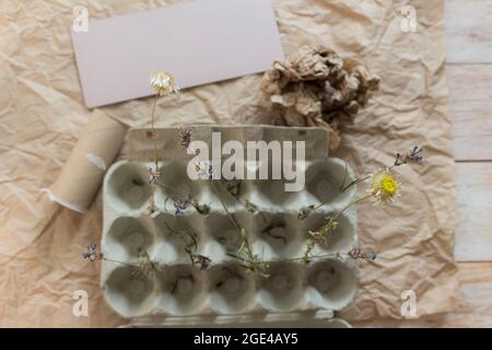 Vassoio aperto isolato con fiori secchi su carta kraft. Concetto creativo di stile di vita ecologico con materiale riciclato. Vista dall'alto. Foto Stock