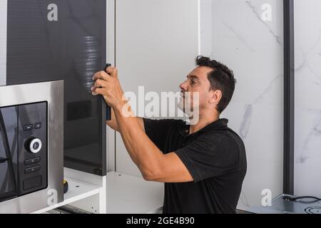 Uomo adulto che monta una cucina in una casa Foto Stock