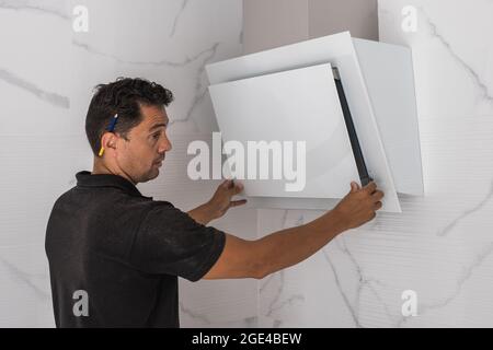 Uomo che monta un ventilatore in cucina Foto Stock