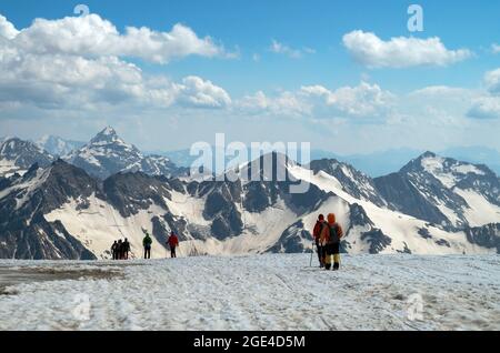 Gli scalatori camminano lungo una catena montuosa. Un gruppo di turisti con zaini, camminando uno dopo l'altro, sale fino alla cima della montagna su un sno Foto Stock