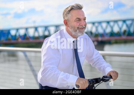 Uomo professionista esperto che guida su uno scooter elettrico attraversando un ponte in un concetto di trasporto urbano e di pendolarismo Foto Stock